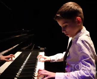 piano lesson student boy playing piano with both hands in shirt and tie